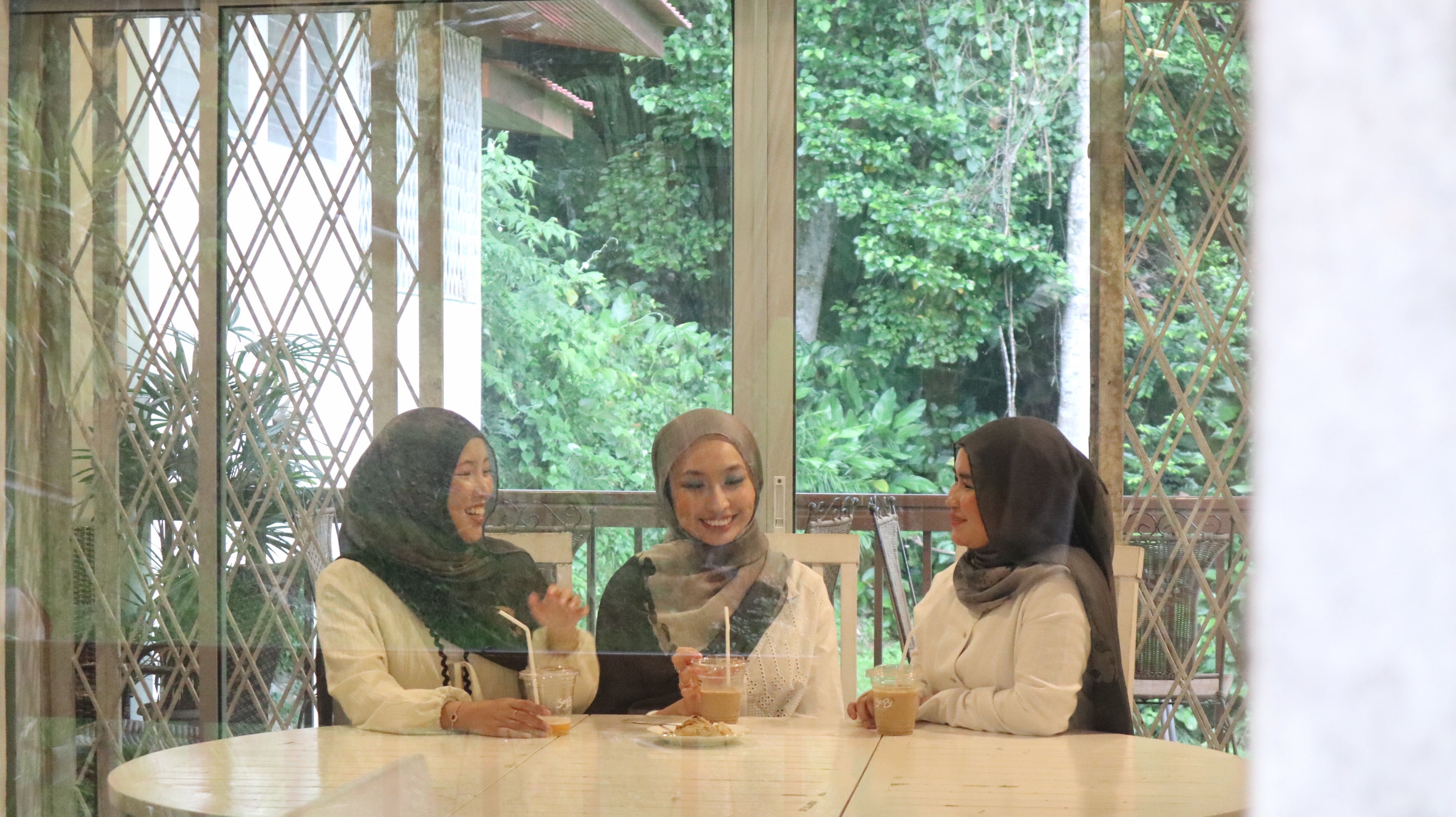 3 ladies in eco friendly hijabs chatting and having coffee